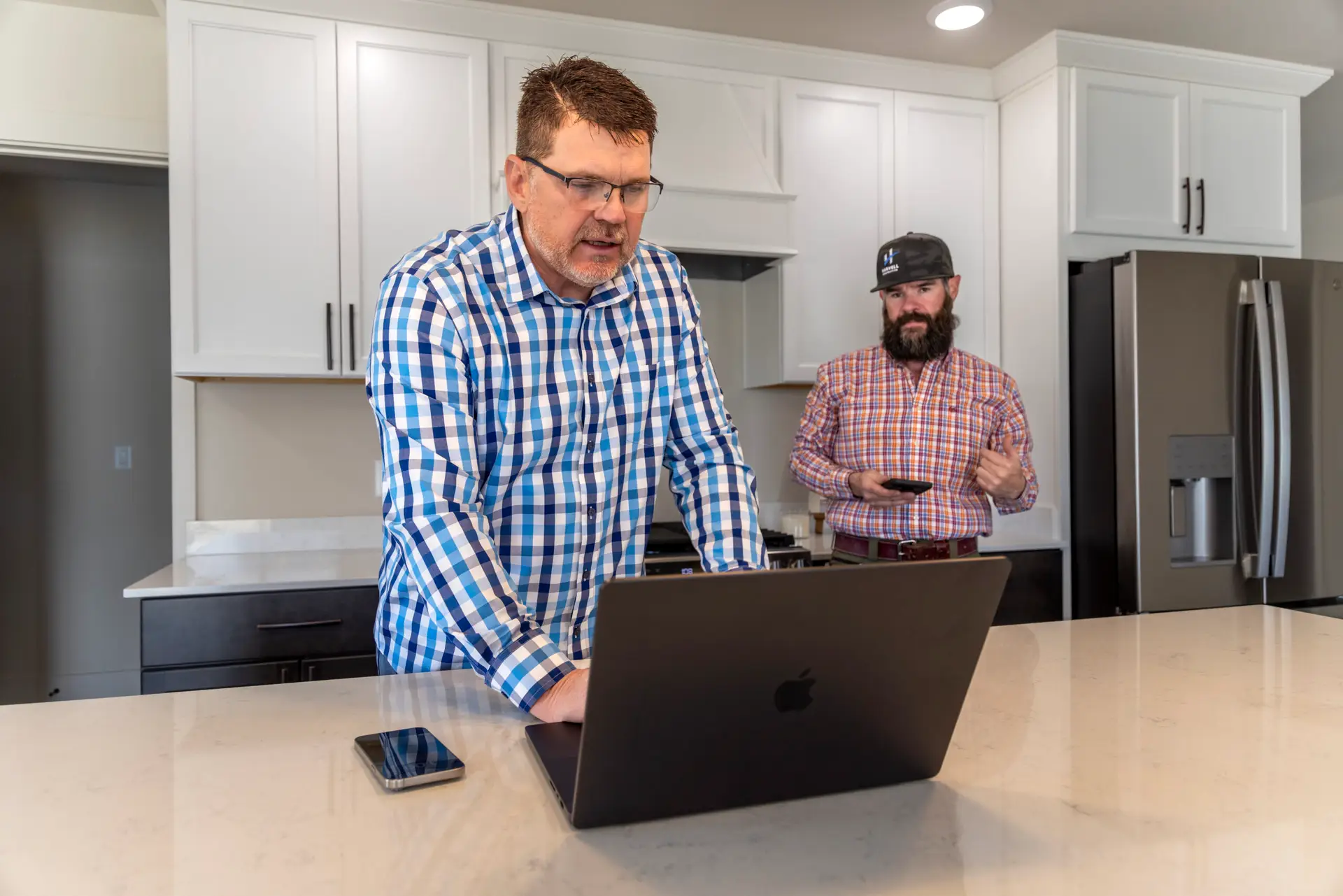 Trent Urwiller, field supervisor, and Chad Harvell of Harvell Homes stands in a custom kitchen designing items together