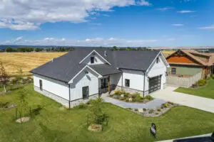 Exterior angled drone photo of a one-story modern farmhouse home built by Harvell Homes in Powell, Wyoming with finished landscaping
