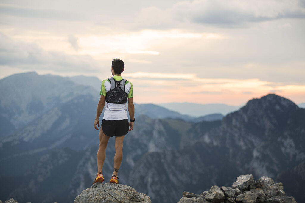 Image of a male runner standing on rock overlooking mountain ranges
